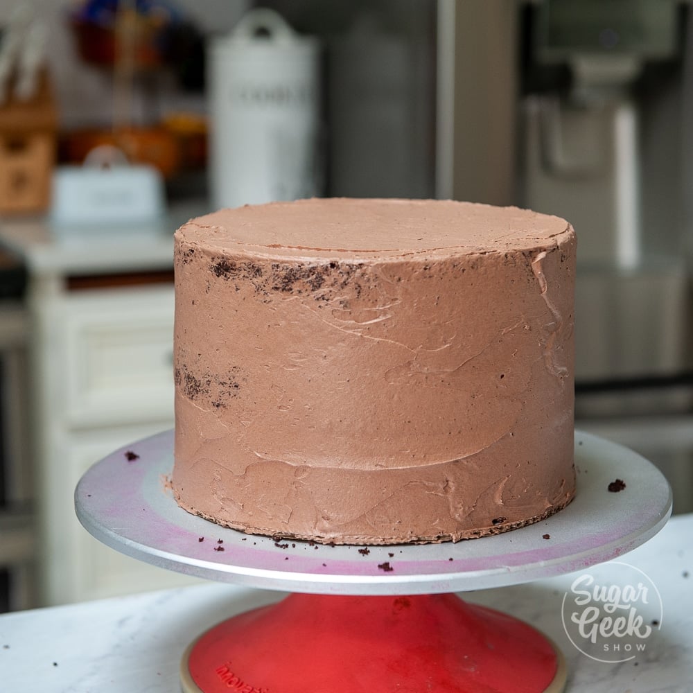 chocolate cake on turntable with thin layer of chocolate buttercream
