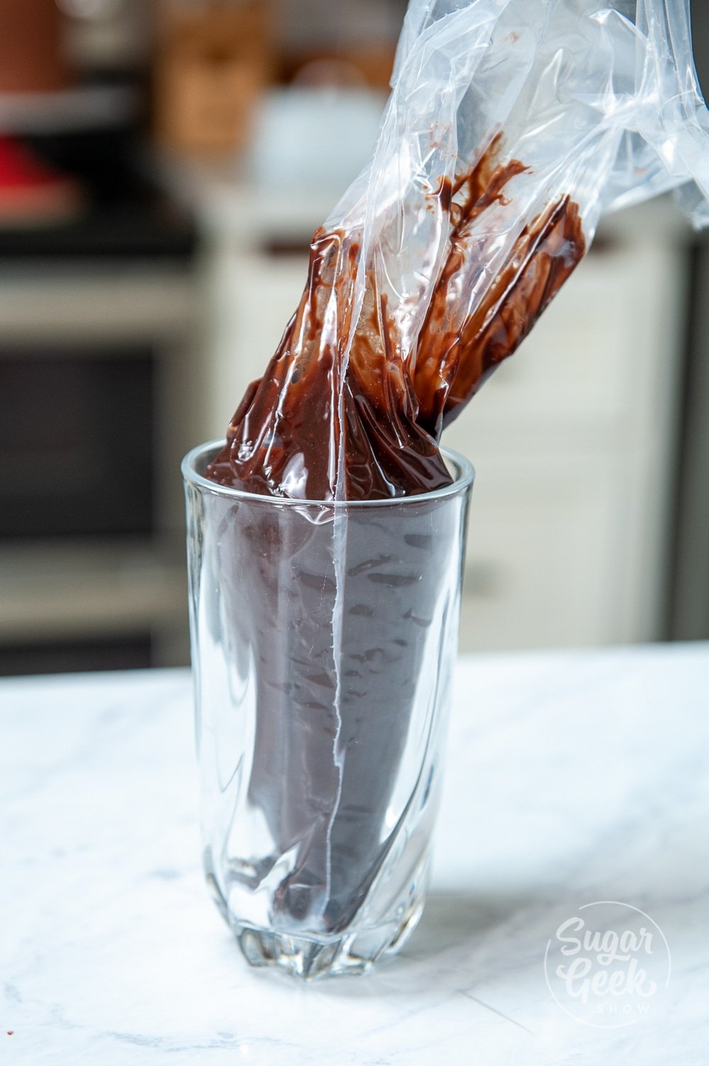 piping bag with chocolate ganache inside a glass cup