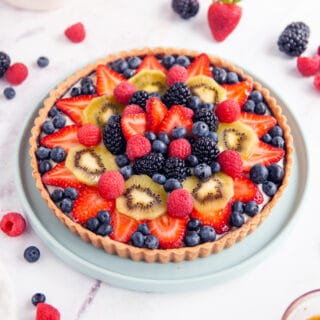 fruit tart on white background with berries surrounding