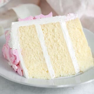closeup of vanilla cake with vanilla buttercream slice on a white plate