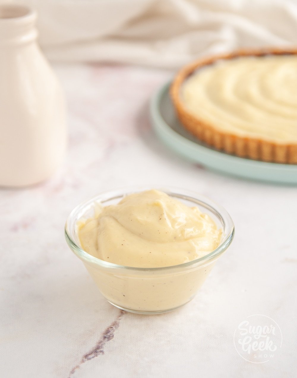 pastry cream in a small glass bowl with tart in the background