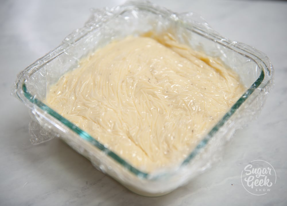 pastry cream in a square glass container with plastic wrap on top