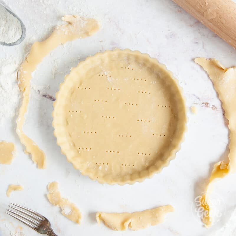top view of tart dough in tart pan with trimmings surrounding it
