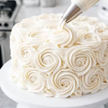 Piping easy buttercream rosettes onto a cake using a 1M star piping tip