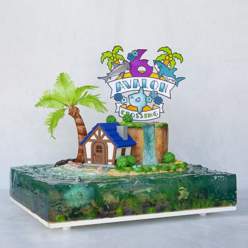 Island made out of cake with cute house, palm tree, cake topper and jelly ocean surrounding island