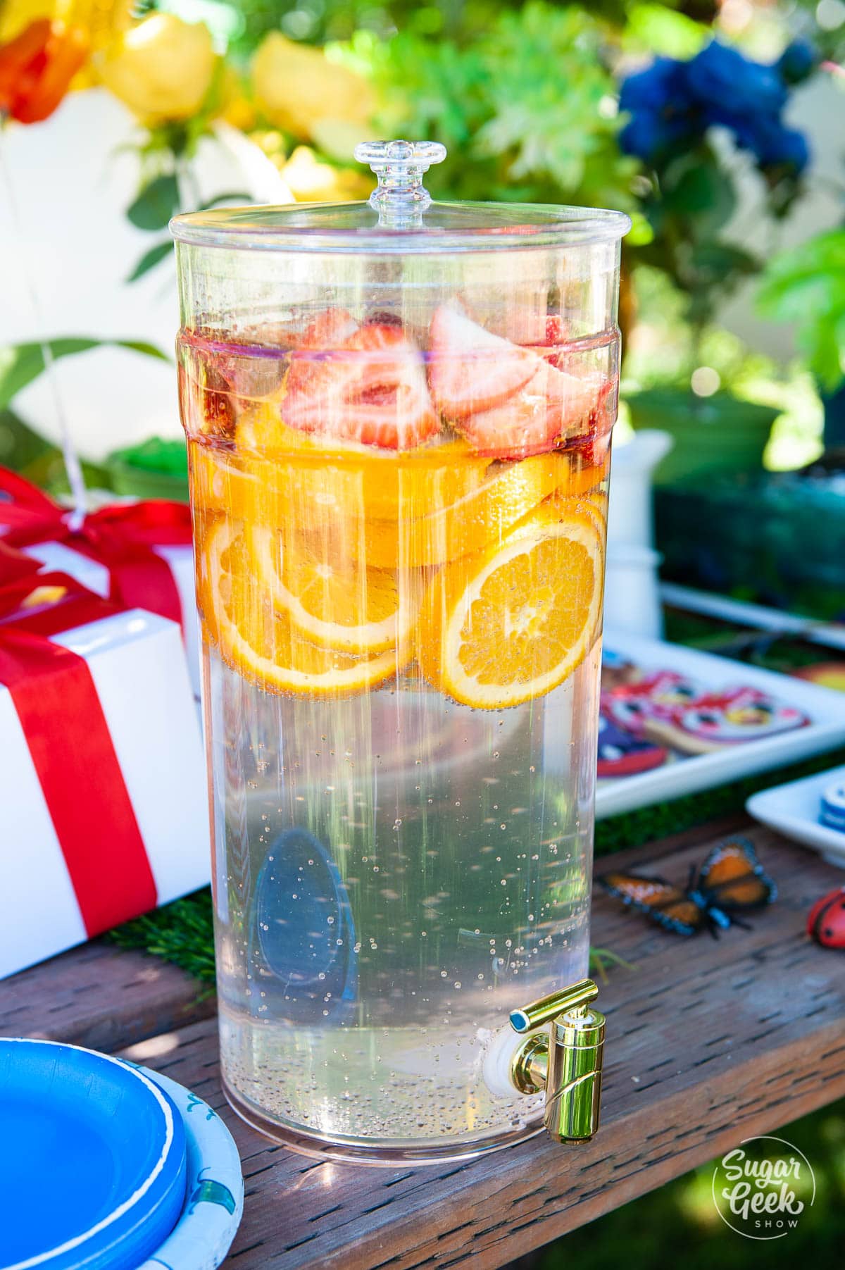 sliced oranges and strawberries in a clear drink despenser 