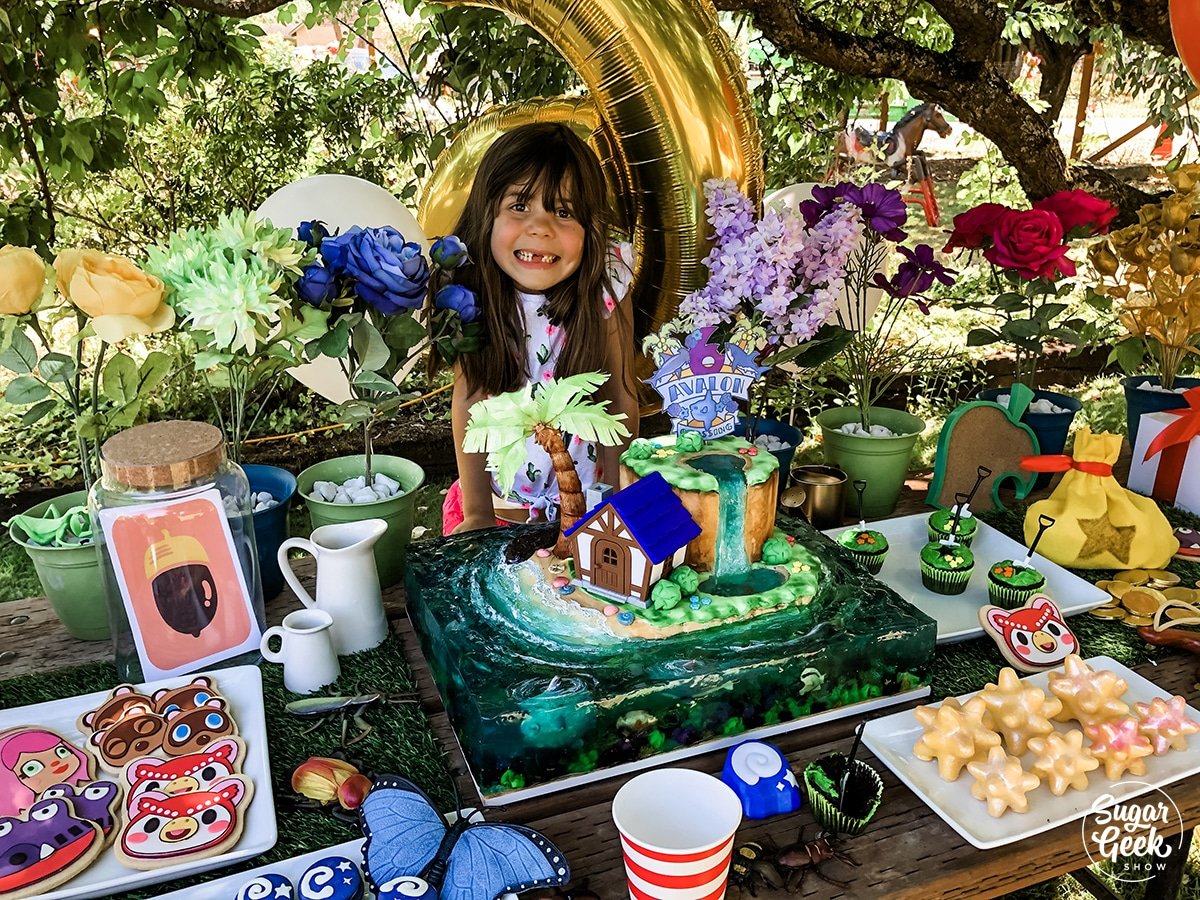 child sitting behind a table filled with animal crossing desserts 