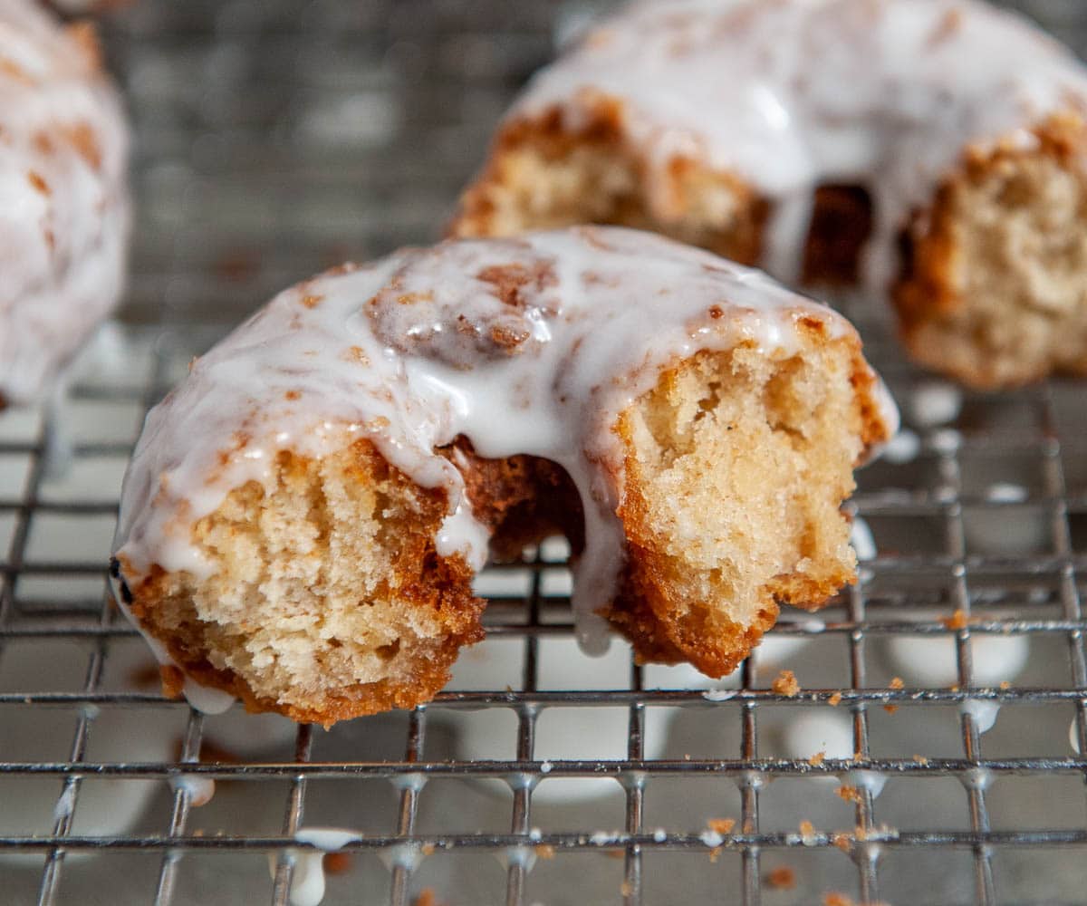 close up of glazed donut broken in half on a cooling rack