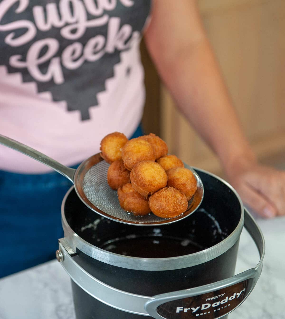 Close up of deep fried donut holes over a fry daddy.