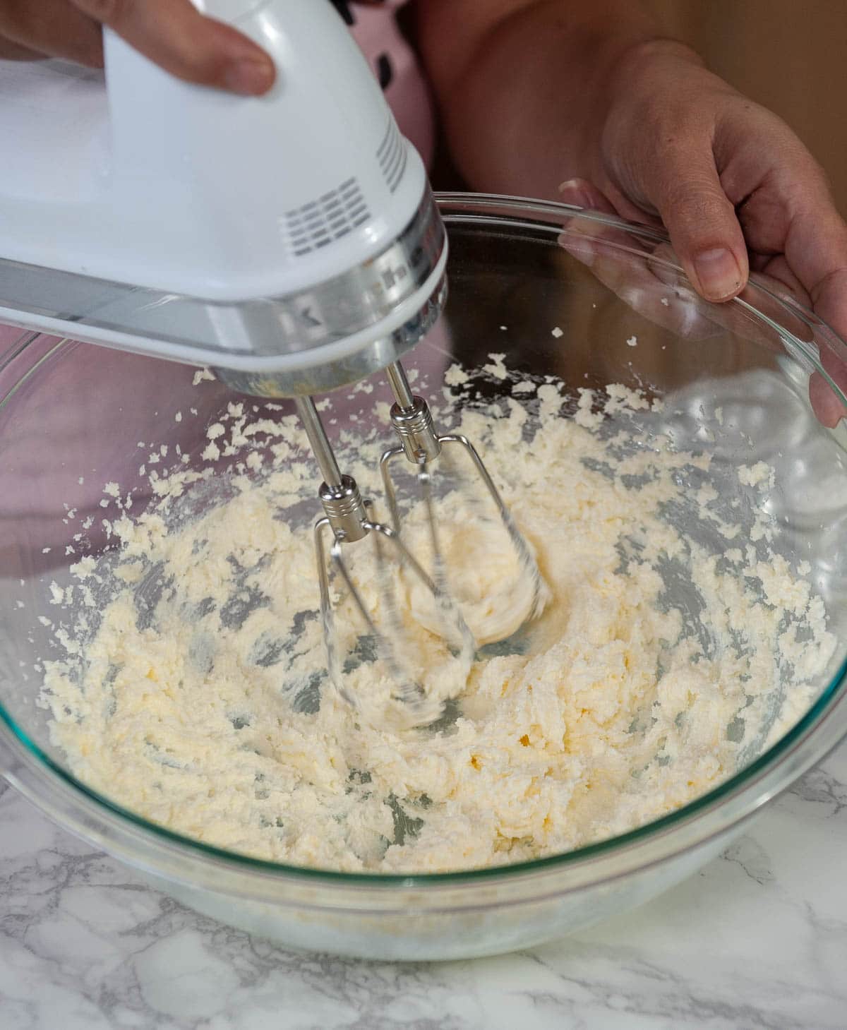 creaming butter and sugar with a hand mixer in a clear bowl