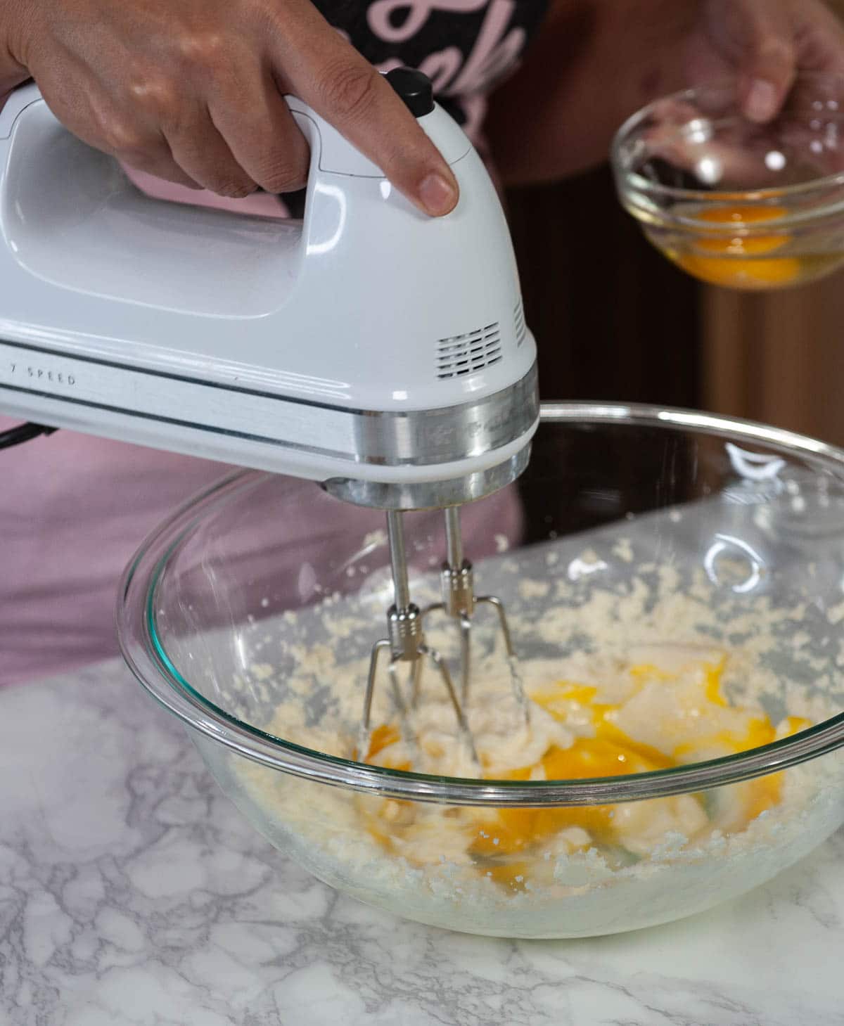 mixing eggs with butter and sugar with a hand mixer in a glass bowl