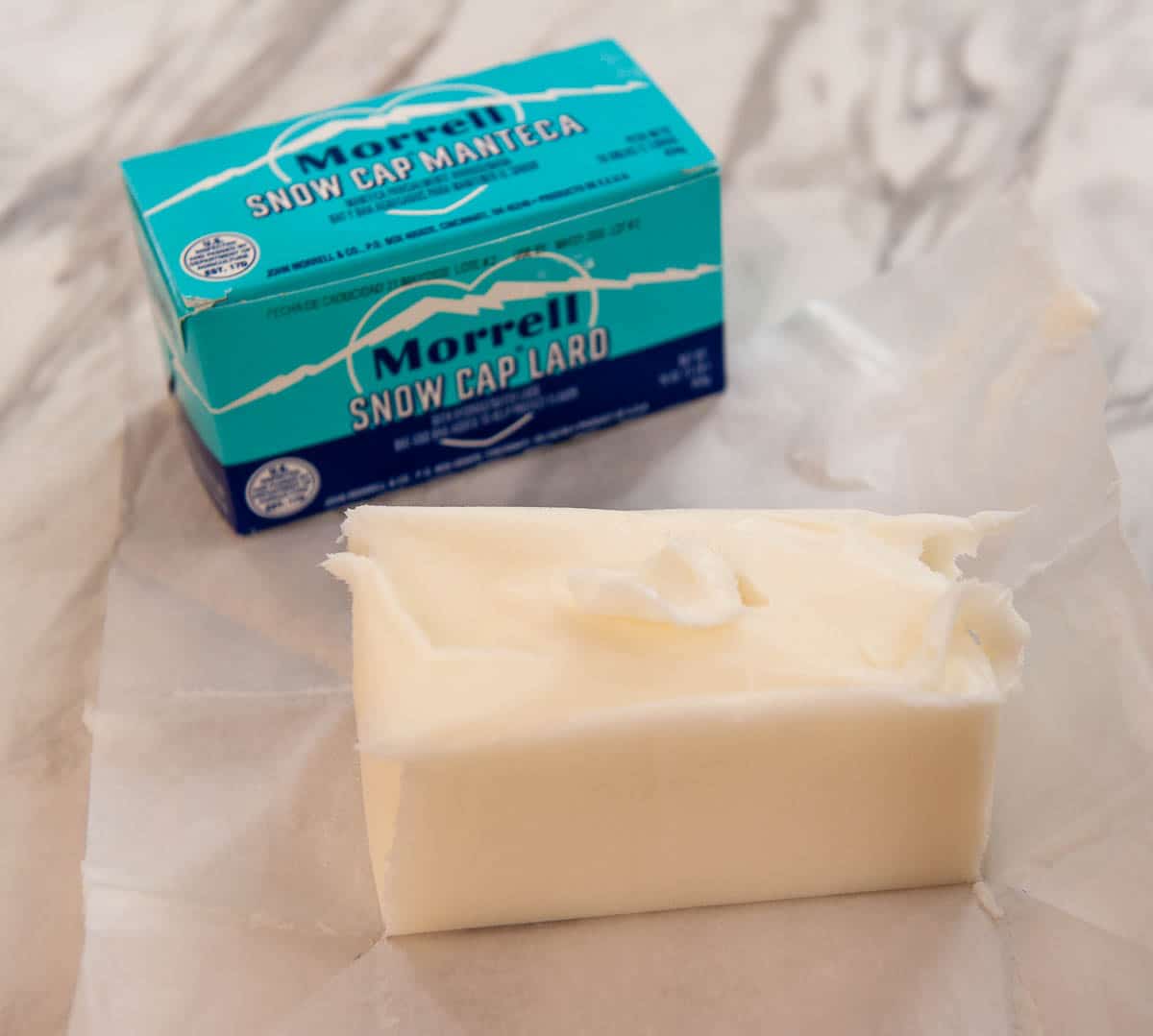 block of lard in front of packaging on a white surface