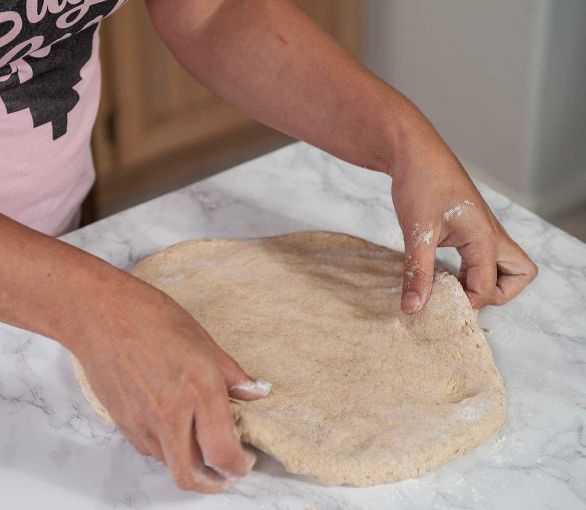 Pressing sourdough discard donut dough onto the countertop.