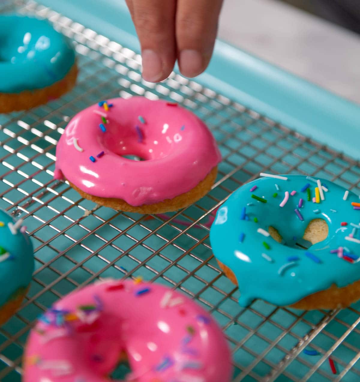 Adding sprinkles to the top of the donuts while the glaze is still wet.