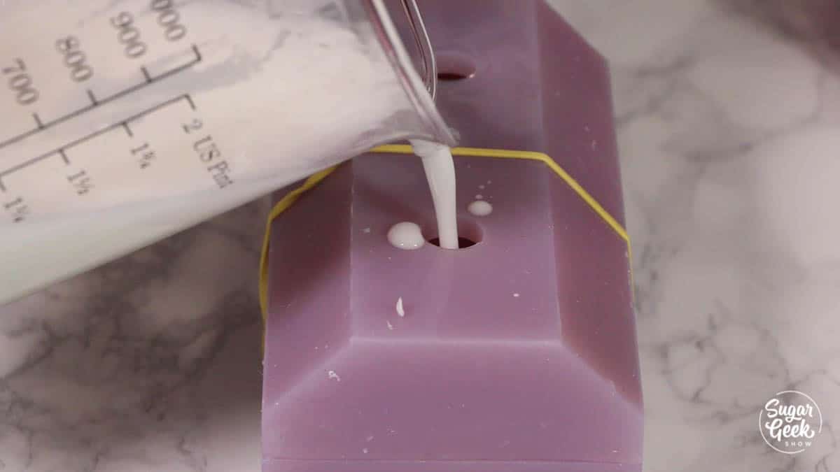 pouring white gelatin into a purple silicone mold