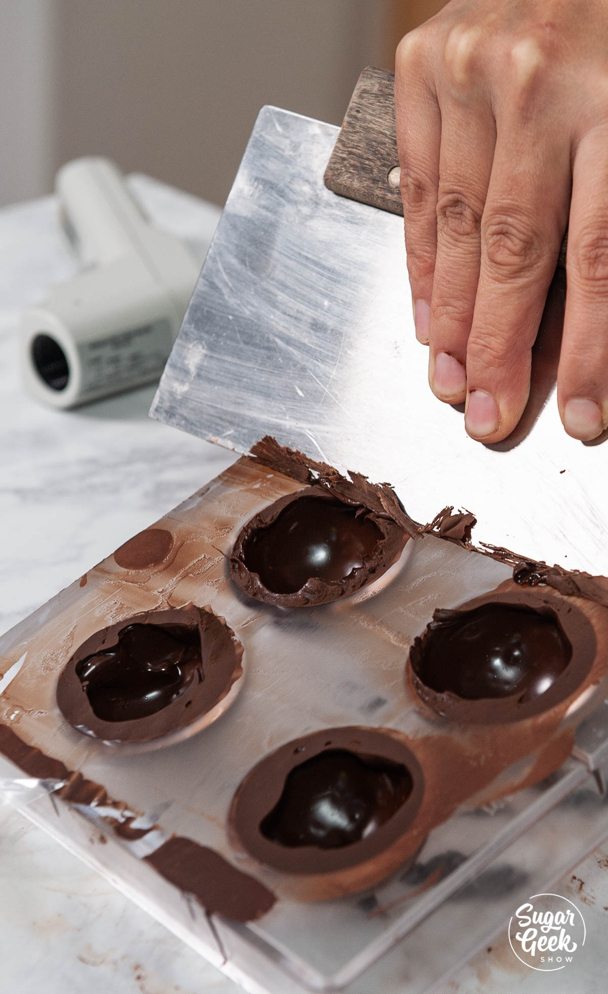 scraping excess chocolate off the mold