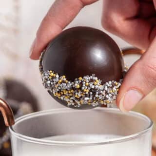 close up of hot chocolate bomb between fingers