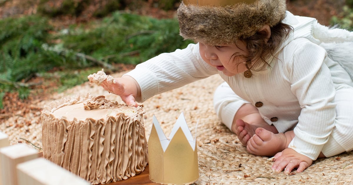 one year old boy reaching towards a smash cake