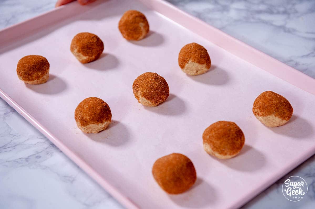 snickerdoodle dough balls on a pink cookie sheet