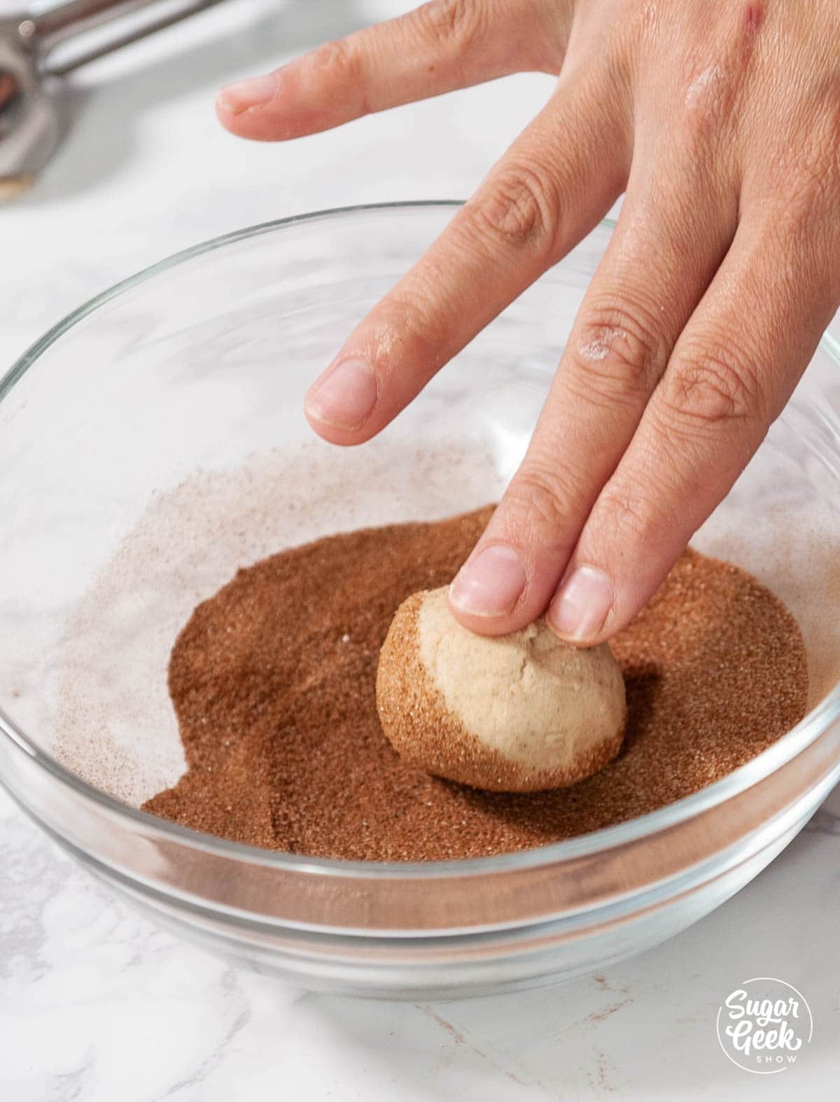 rolling snickerdoodle cookie ball in cinnamon sugar
