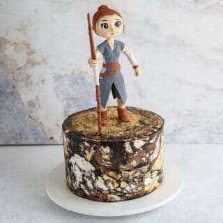 Marble buttercream cake tier with cute standing cake topper holding a staff