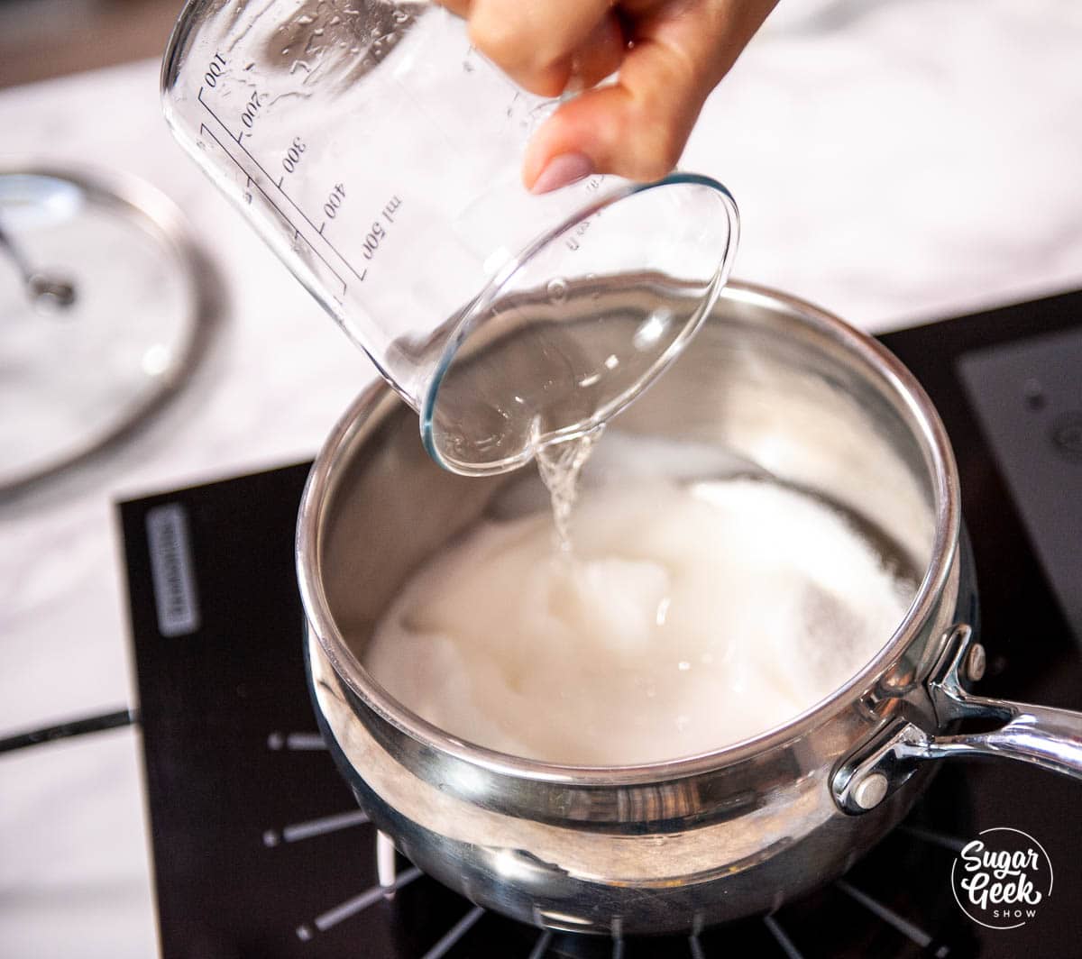 hand pouring corn syrup into saucepan