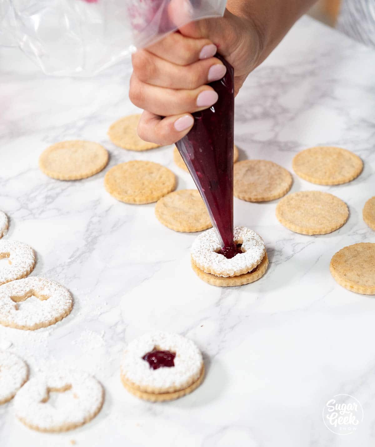 filling the center of a linzer cookie with more filling