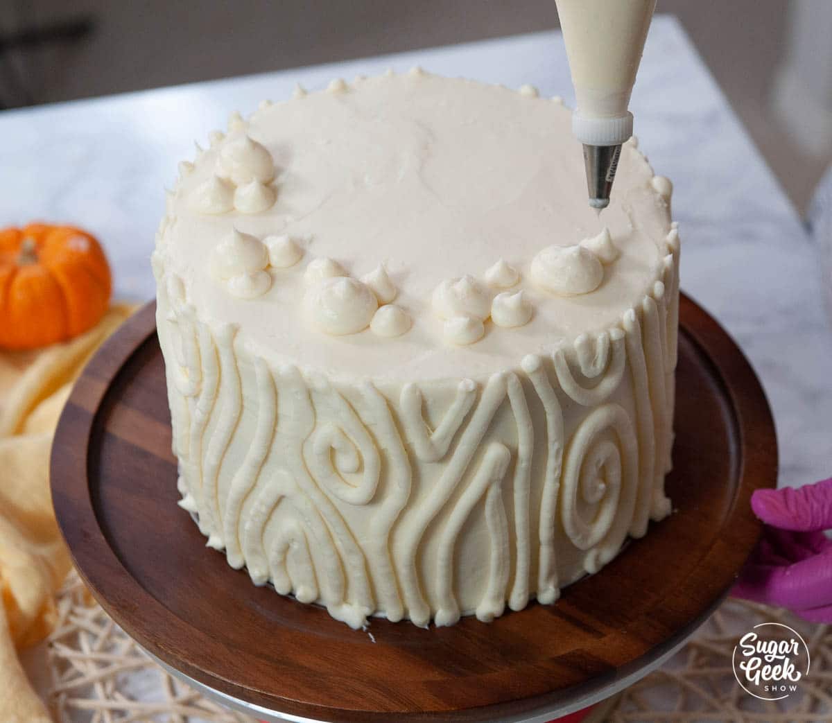 piping dollops of cream cheese frosting on top of the cake