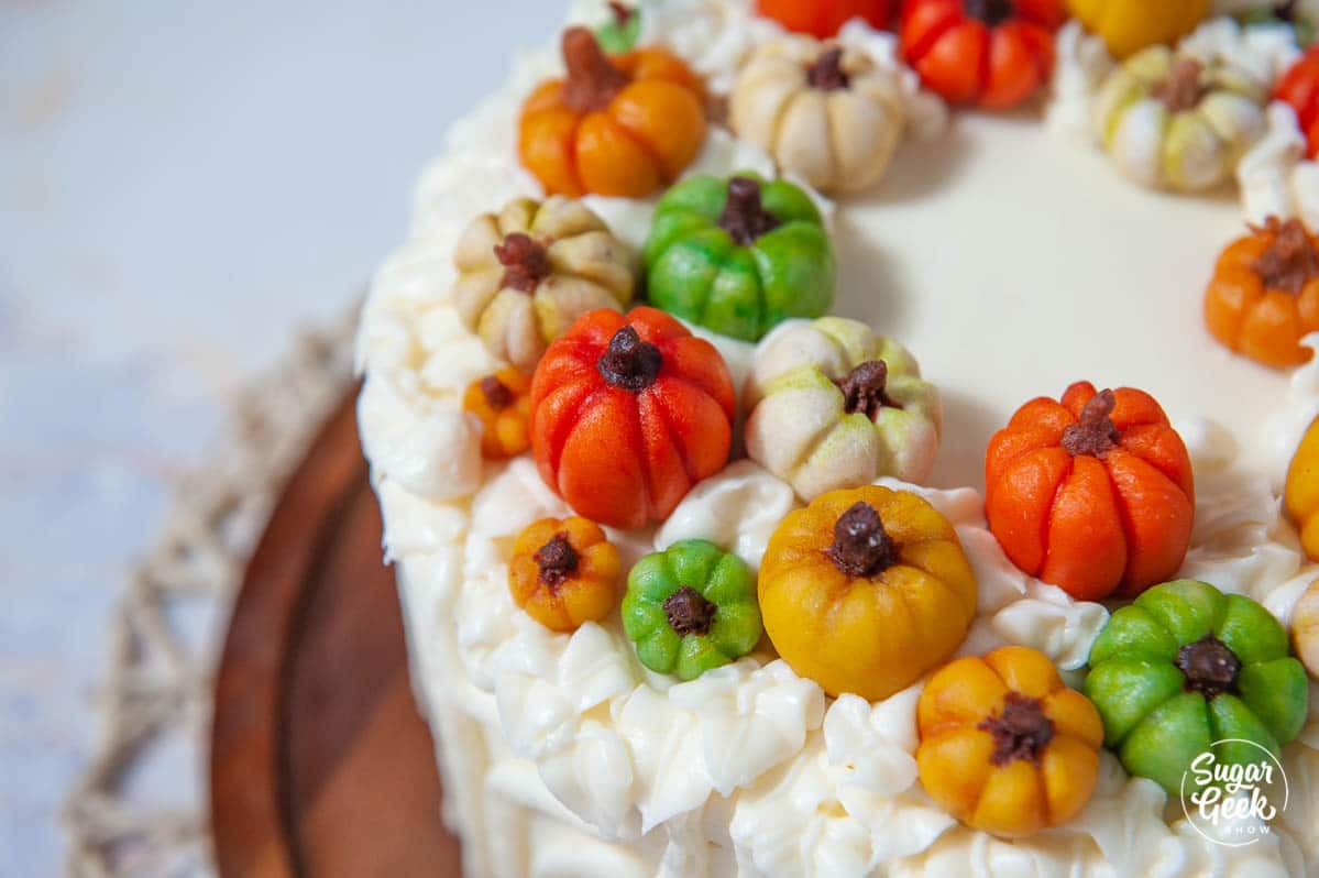 Close-up of marzipan pumpkins and piped cream cheese frosting on top of the pumpkin spice cake.