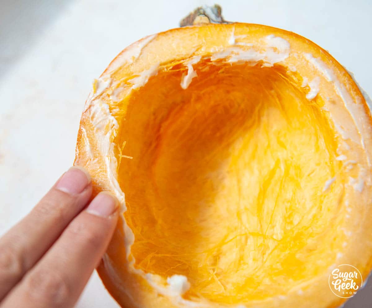 hand applying shortening to a cut pumpkin