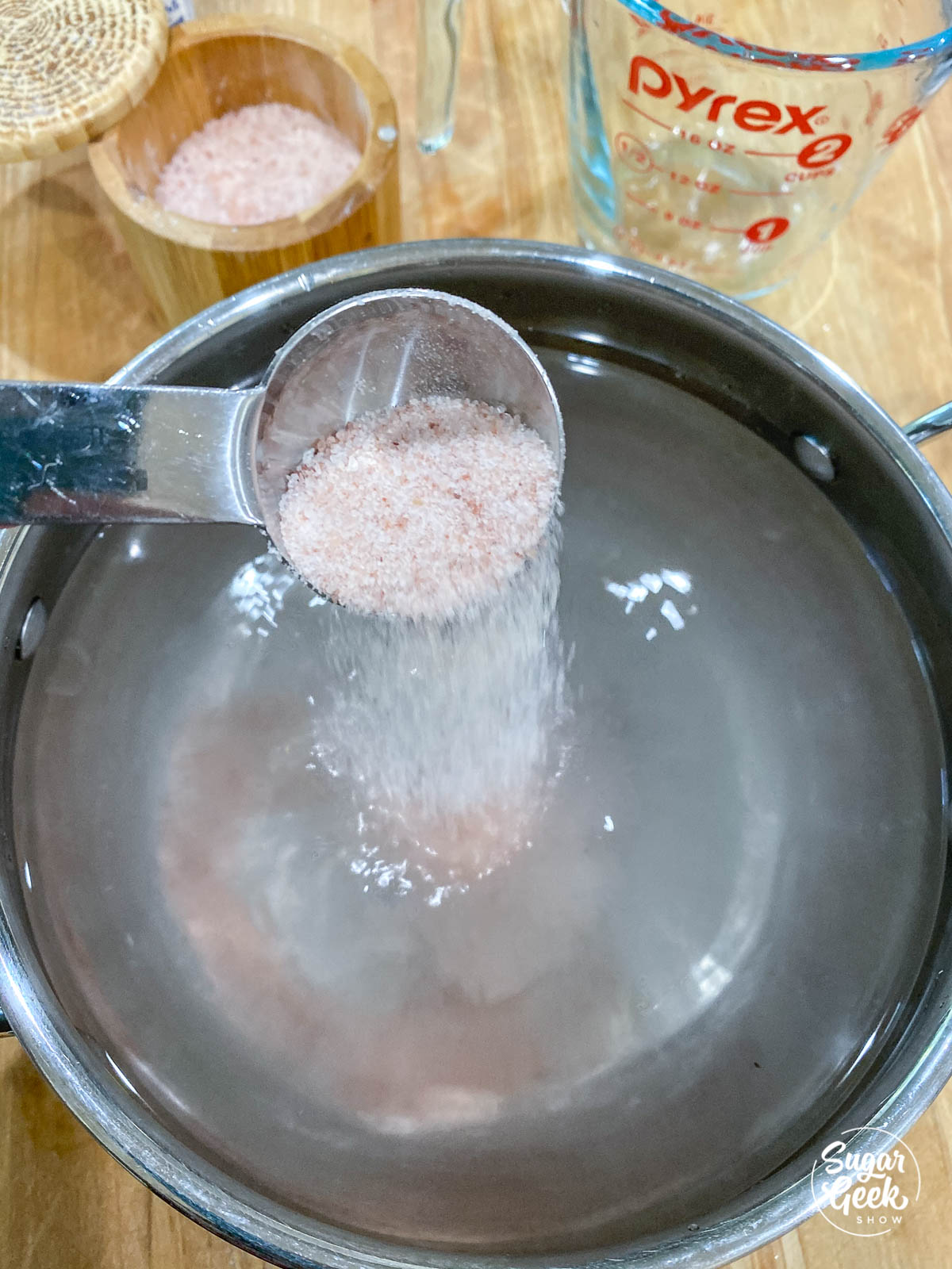 adding salt to water in a stainless steel pot shot from overhead