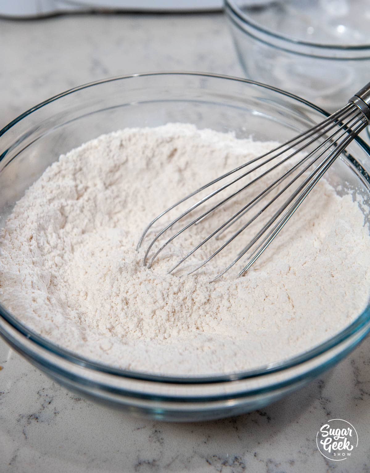 Dry ingredients mixed together in a glass bowl with a whisk. 