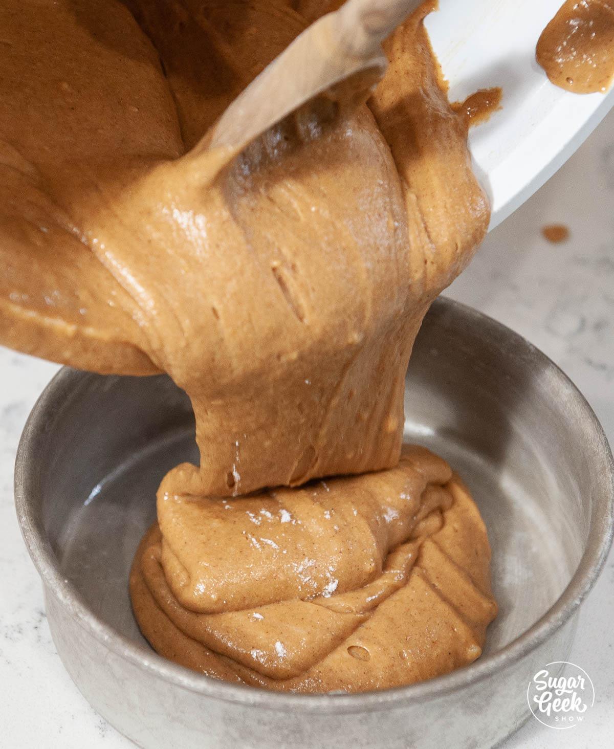 pouring gingerbread cake batter into cake pans