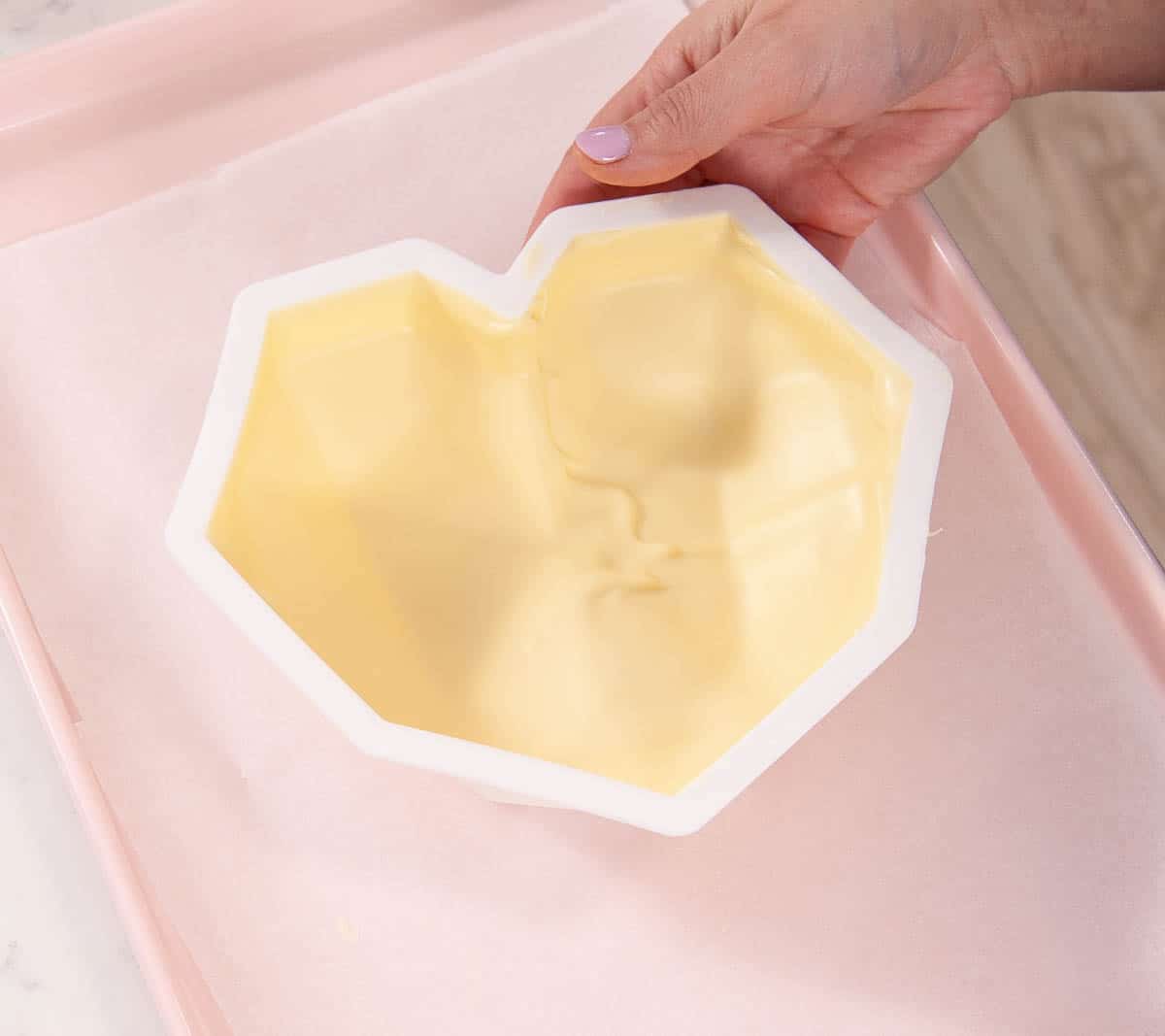 chocolate heart mold on a pink sheet pan