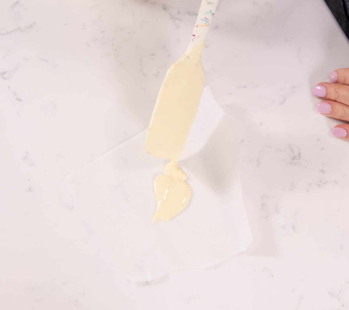 spatula spooning white chocolate onto parchment paper