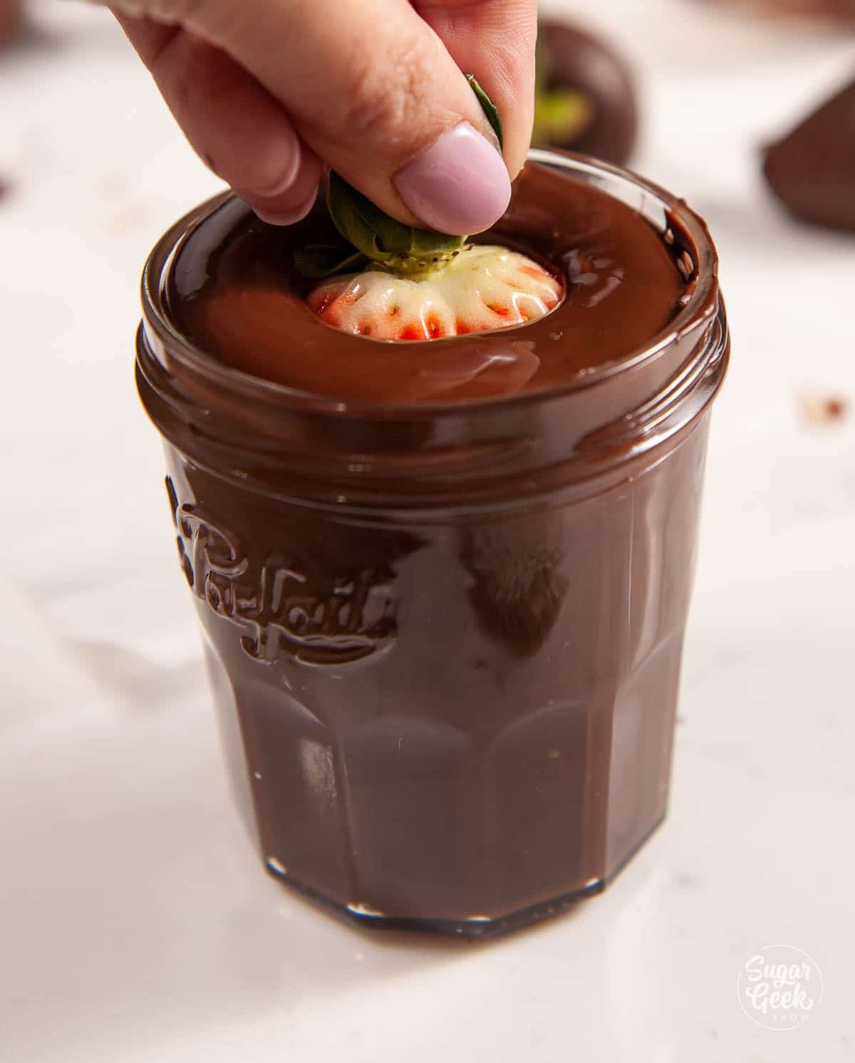 dipping a strawberry in melted chocolate