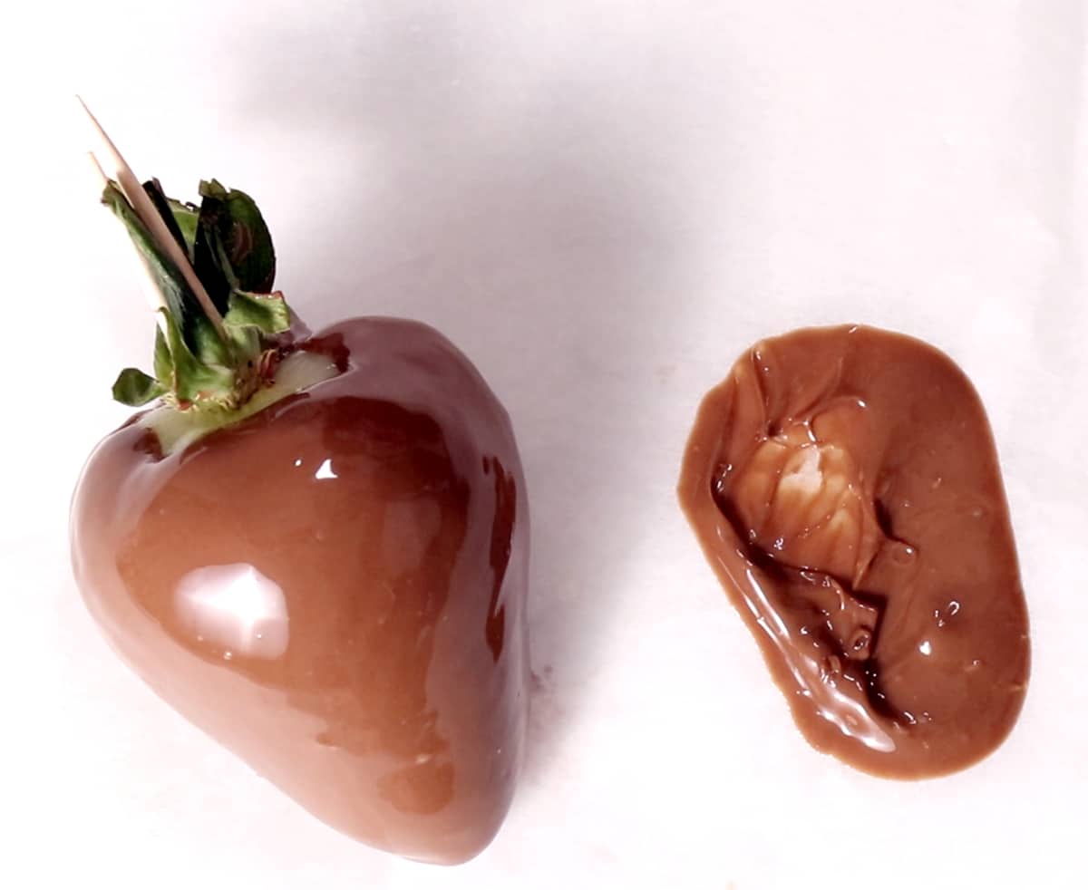 strawberry covered in chocolate on parchment paper shot from above