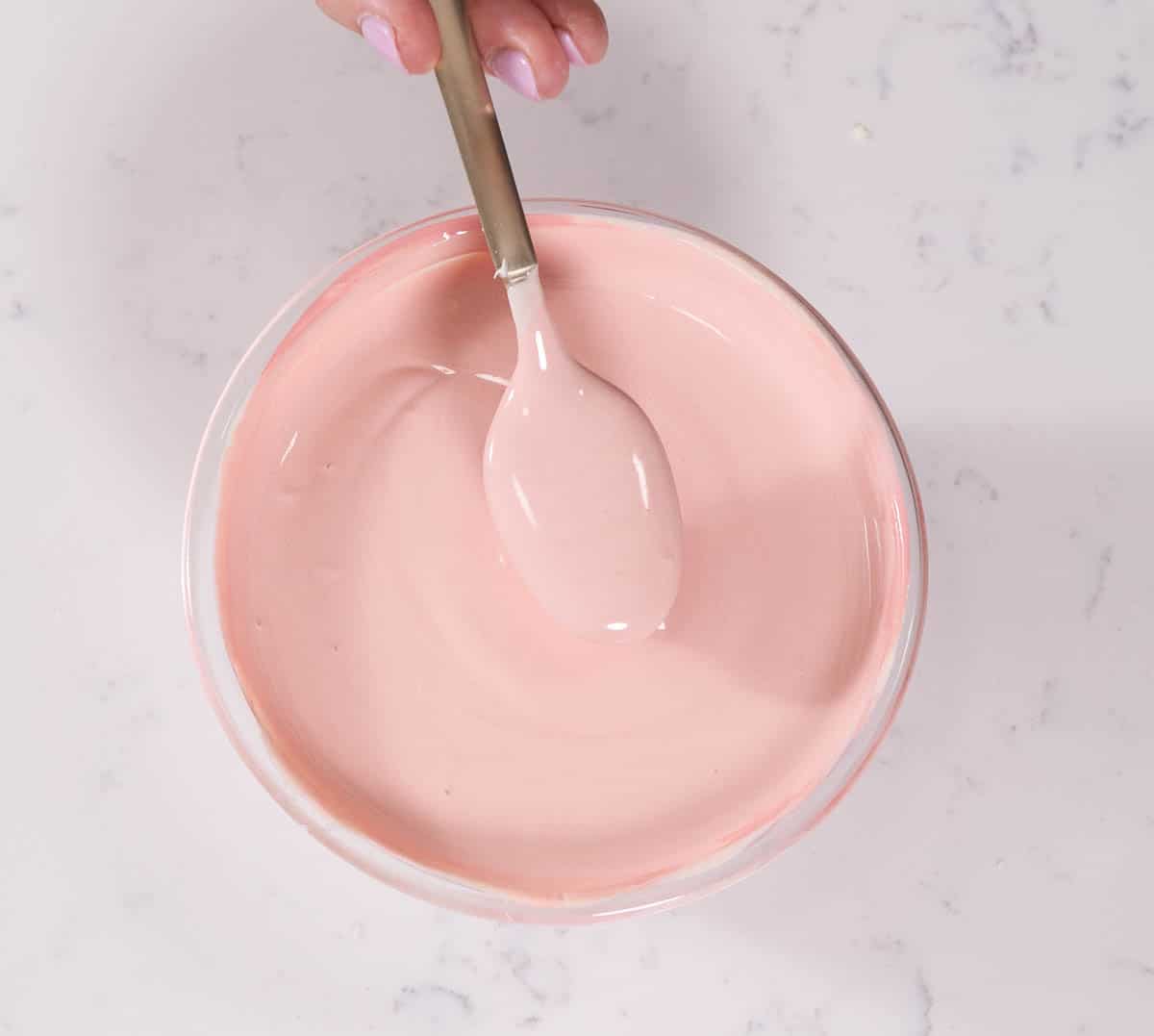 white chocolate colored pink in a bowl with a spoon