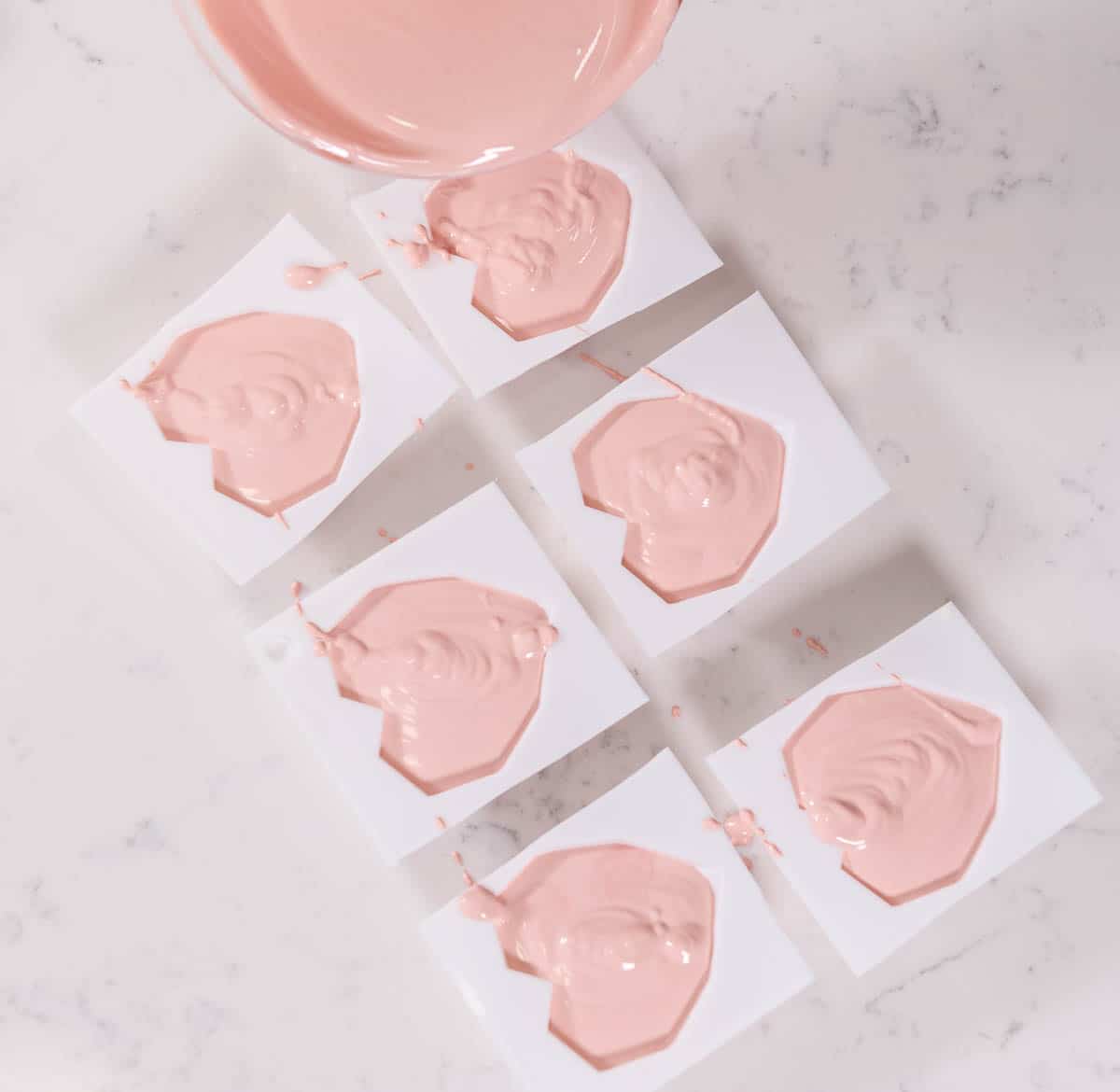 heart molds being filled with melted pink chocolate