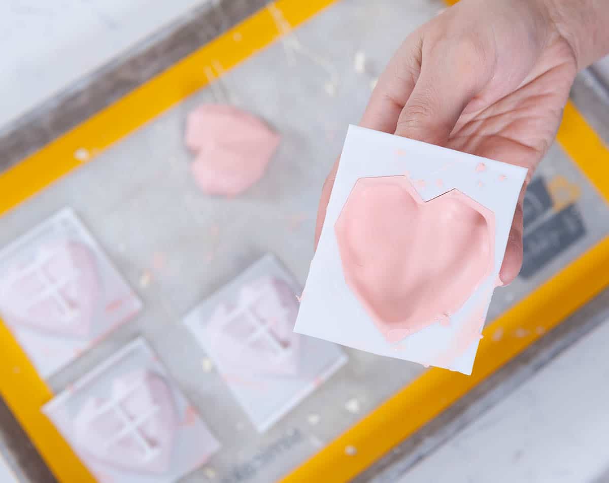 heart hold chocolate hold held in a hand over a sheet pan