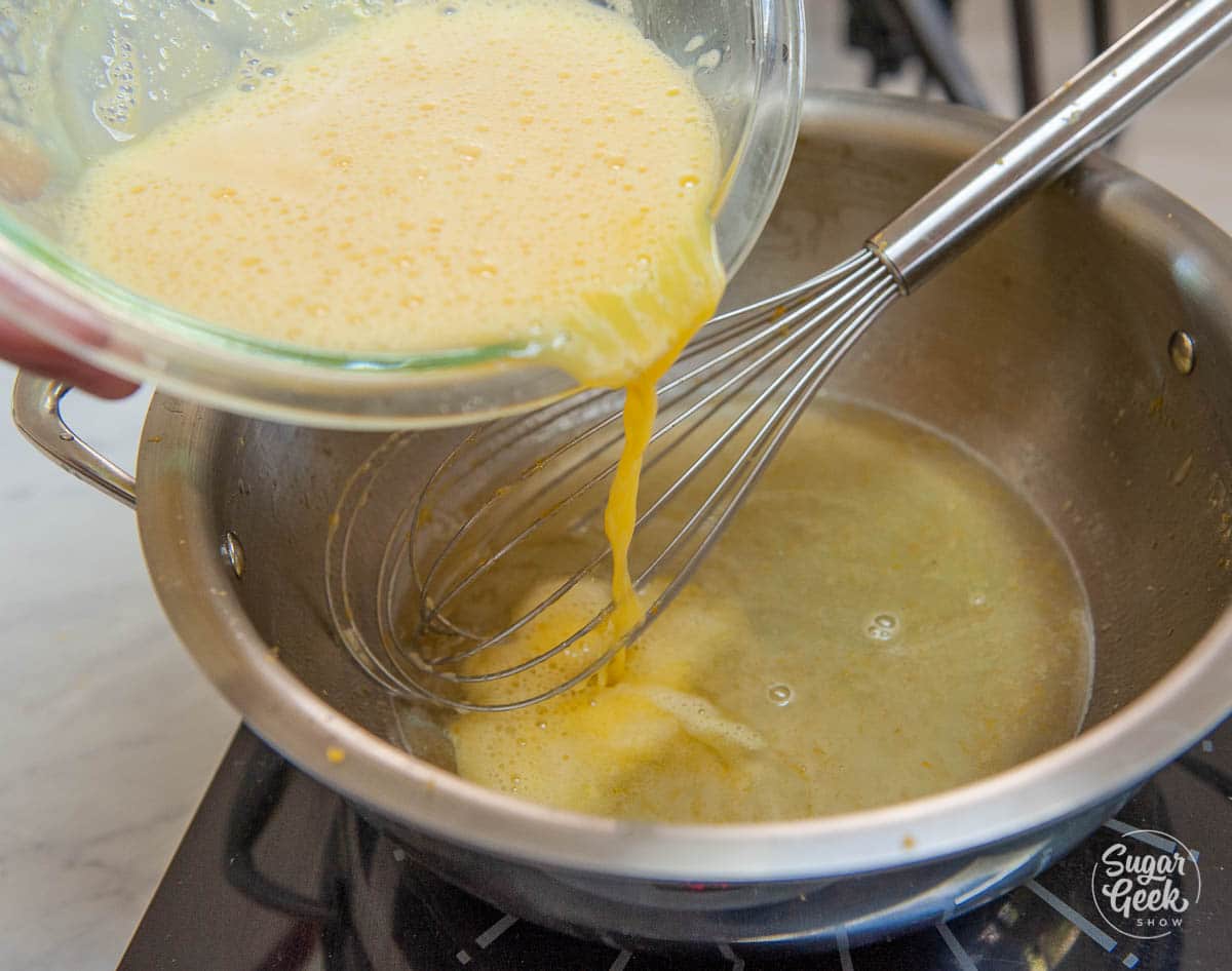 adding tempered egg mixture to hot lemon juice