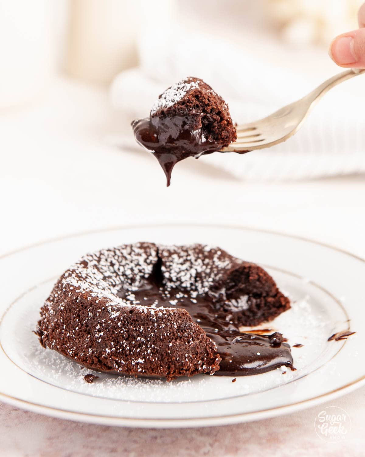 fork lifting a piece of lava cake over a white plate