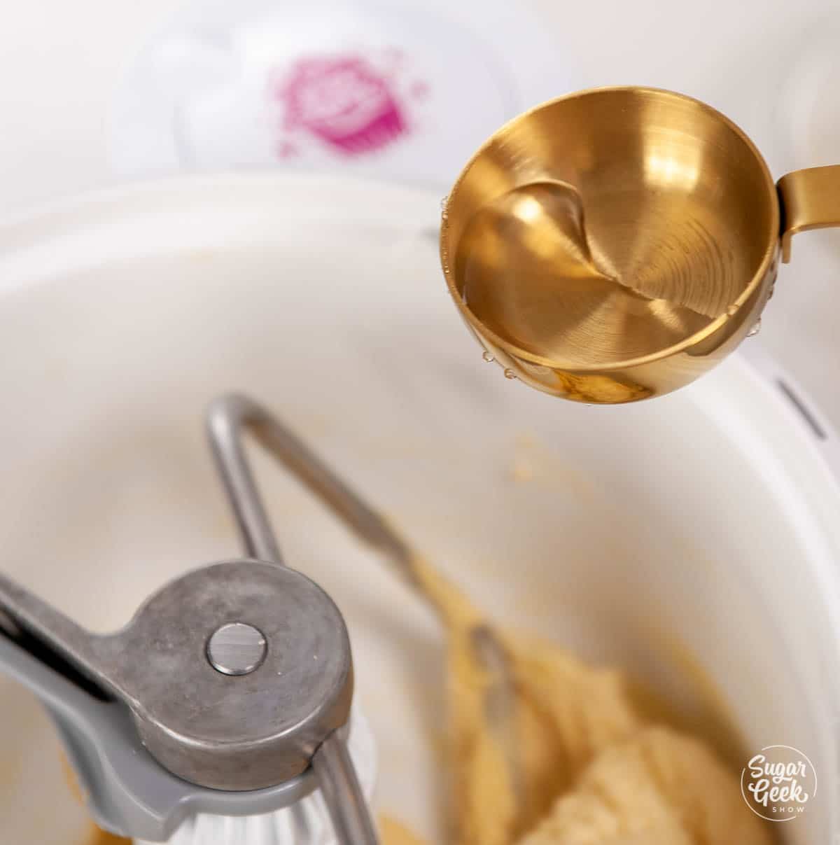 Gold measuring cup of water over a mixing bowl of brioche dough.