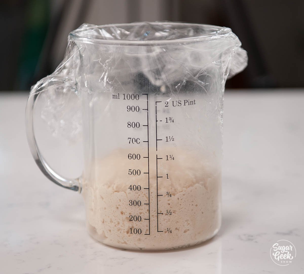 closeup of yeast mixture rising in a measuring cup
