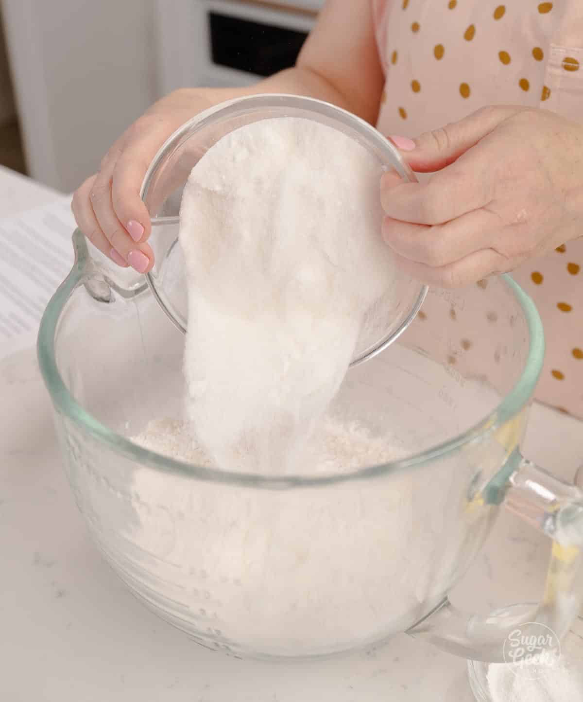 adding dry ingredients to a glass mixing bowl