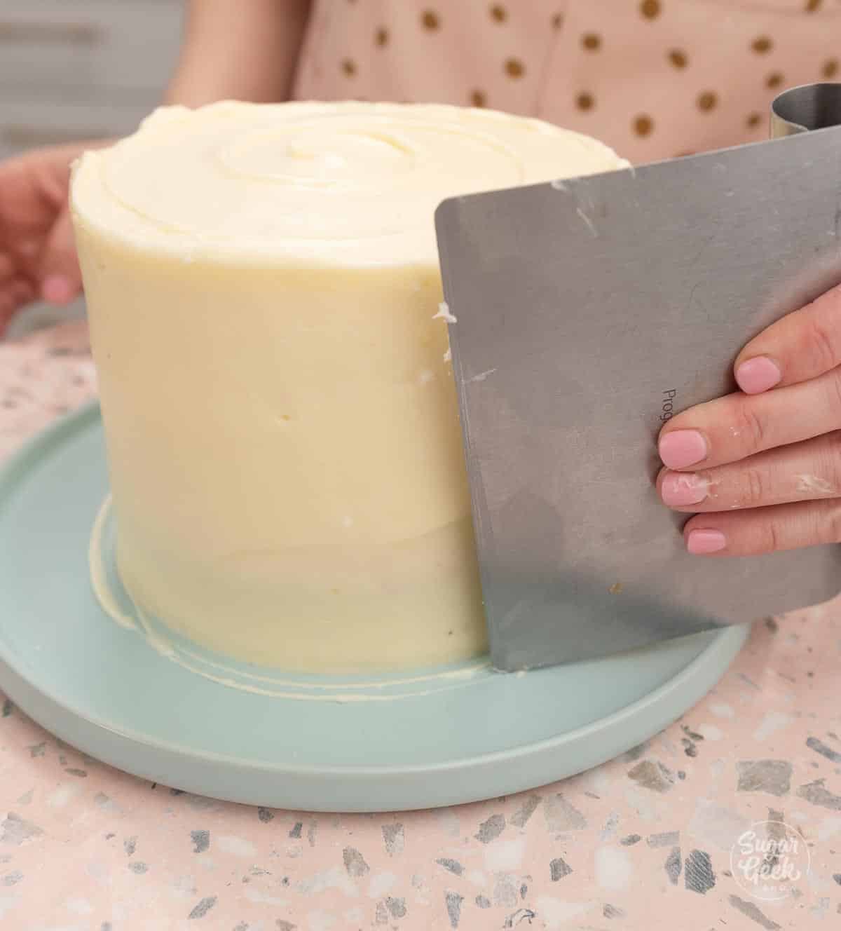 smoothing a cake with a bench scraper