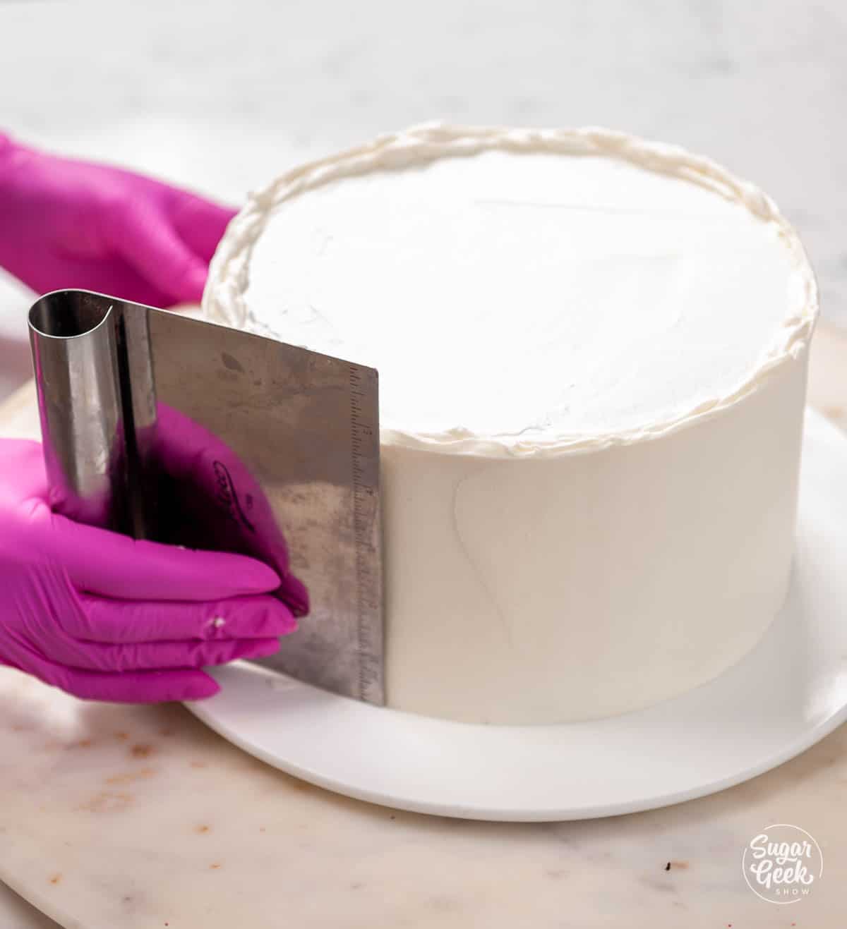 smoothing the sides of the ice cream cake with a bench scraper