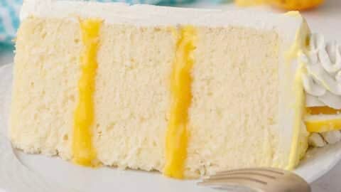 lemon layer cake slice with lemon curd filling and buttercream on a white plate
