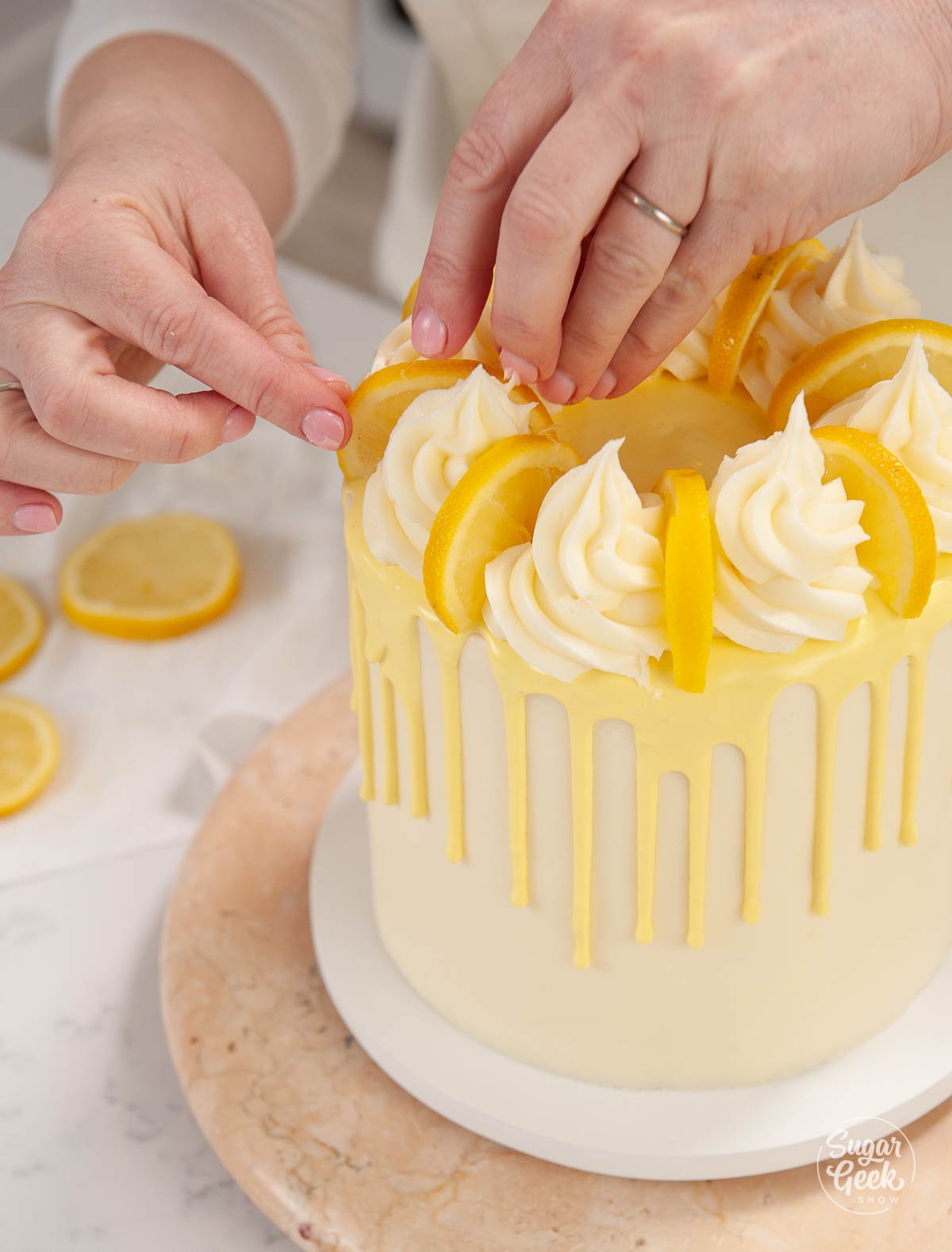 adding lemon slices to the top of a lemon layer cake