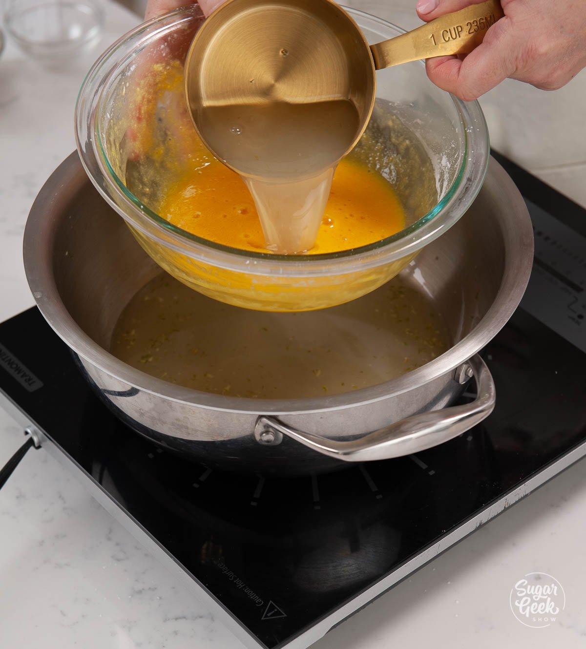 adding hot lime juice mixture to egg yolk mixture with a measuring cup